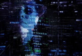pessoa de óculos escuro e chapéu com códigos na tela Ransomware